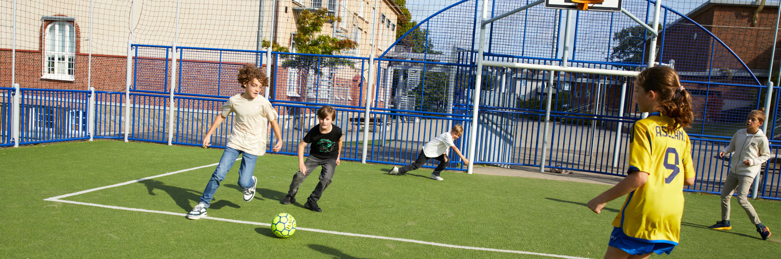 Des enfants jouent au football sur un terrain de sport public.